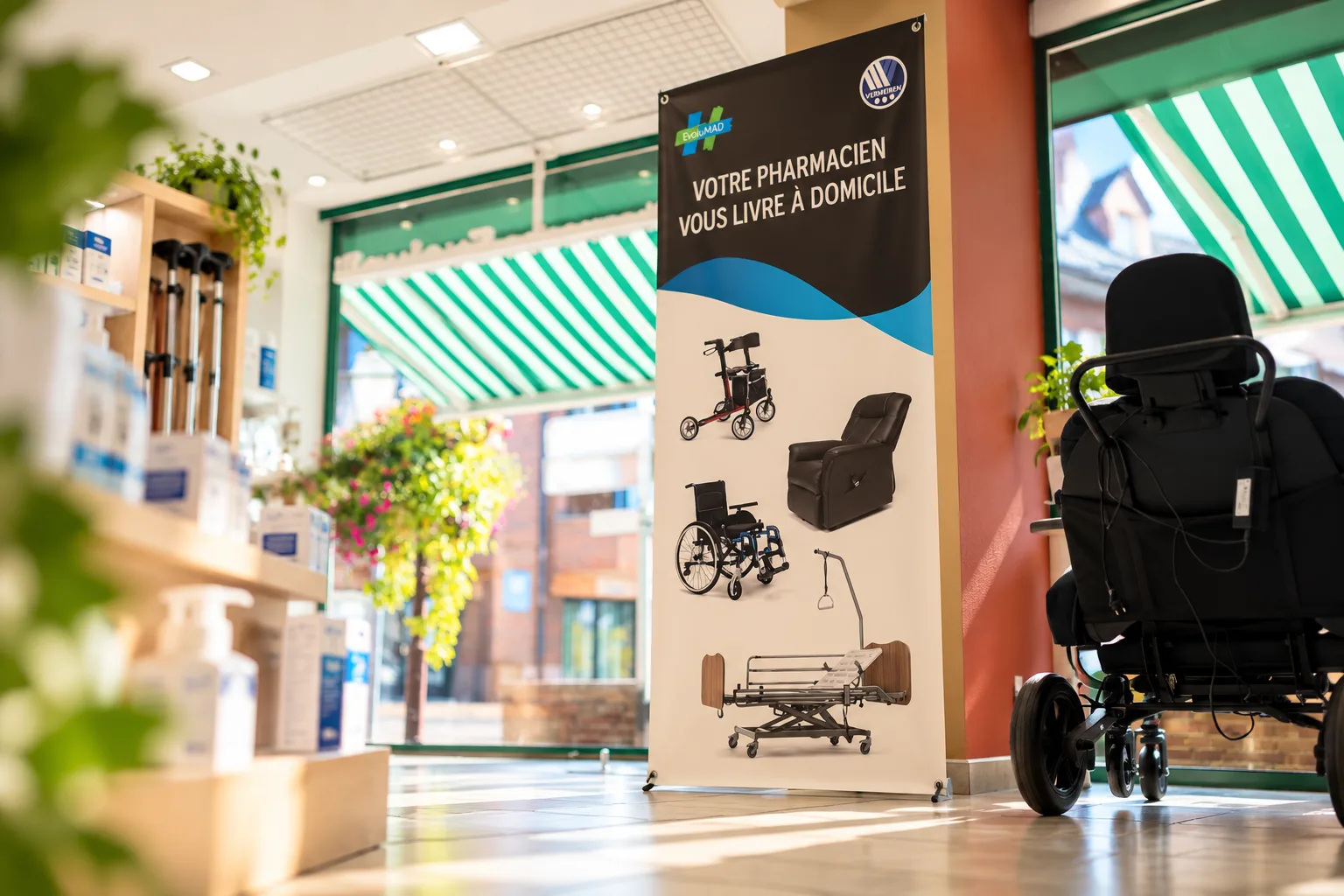 Affiche EvoluMAD présentant un déambulateur, un fauteuil roulant et un lit médicalisé, à côté d'un fauteuil roulant électrique à la Pharmacie Thermale.